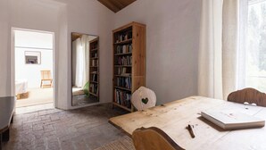A room with a wooden table, a bookshelf, a mirror, and a chair.