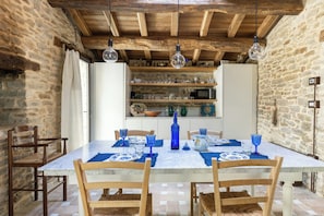 A dining area with a marble table, wooden chairs, and a stone wall.