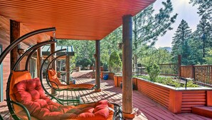 Une terrasse en bois avec deux chaises longues, une clôture en bois et une vue sur les arbres.