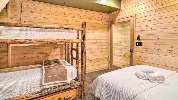 A wooden cabin room with bunk beds, a single bed, and a door. - Luxe Prescott Natl Forest Home w/ Huge Deck (Prescott)