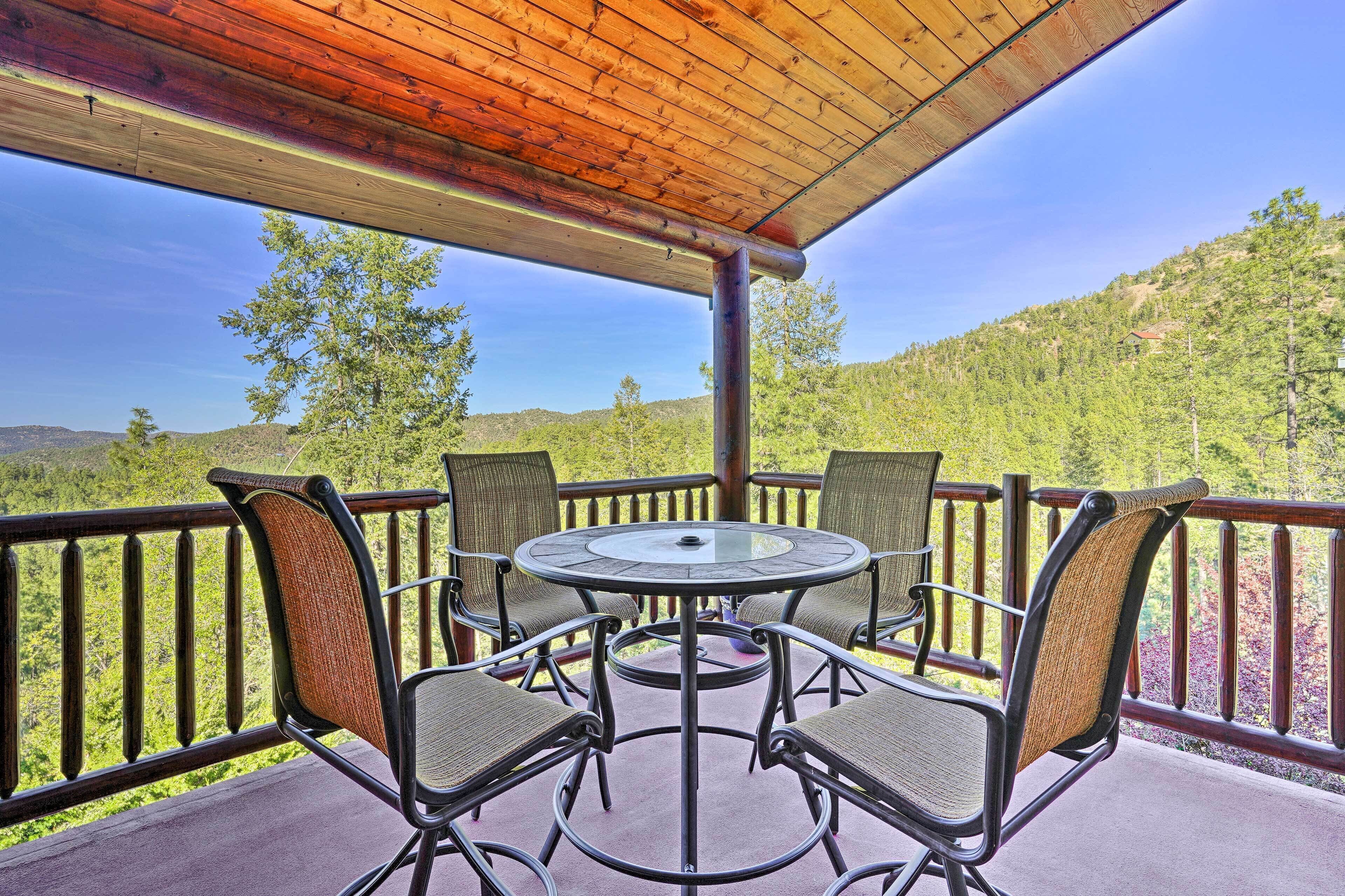 Un espace extérieur abrité, avec une table et des chaises, offrant une vue sur un paysage montagneux.