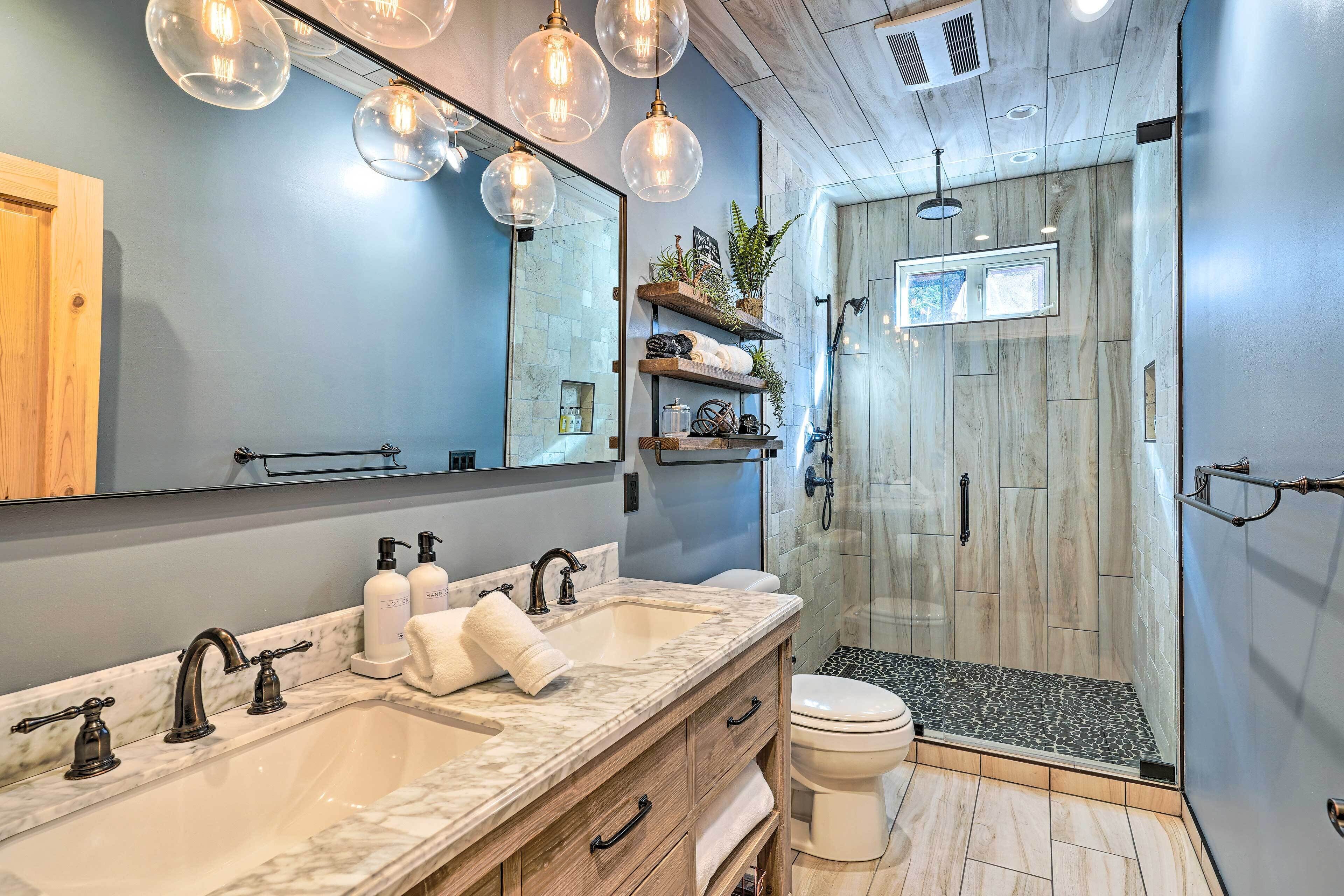 Un baño moderno con lavamanos doble, un espejo grande y una ducha a ras de suelo.