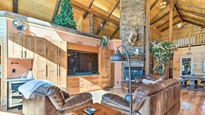 A spacious living area with leather sofas, a fireplace, and a stone accent wall. - Luxe Prescott Natl Forest Home w/ Huge Deck (Prescott)