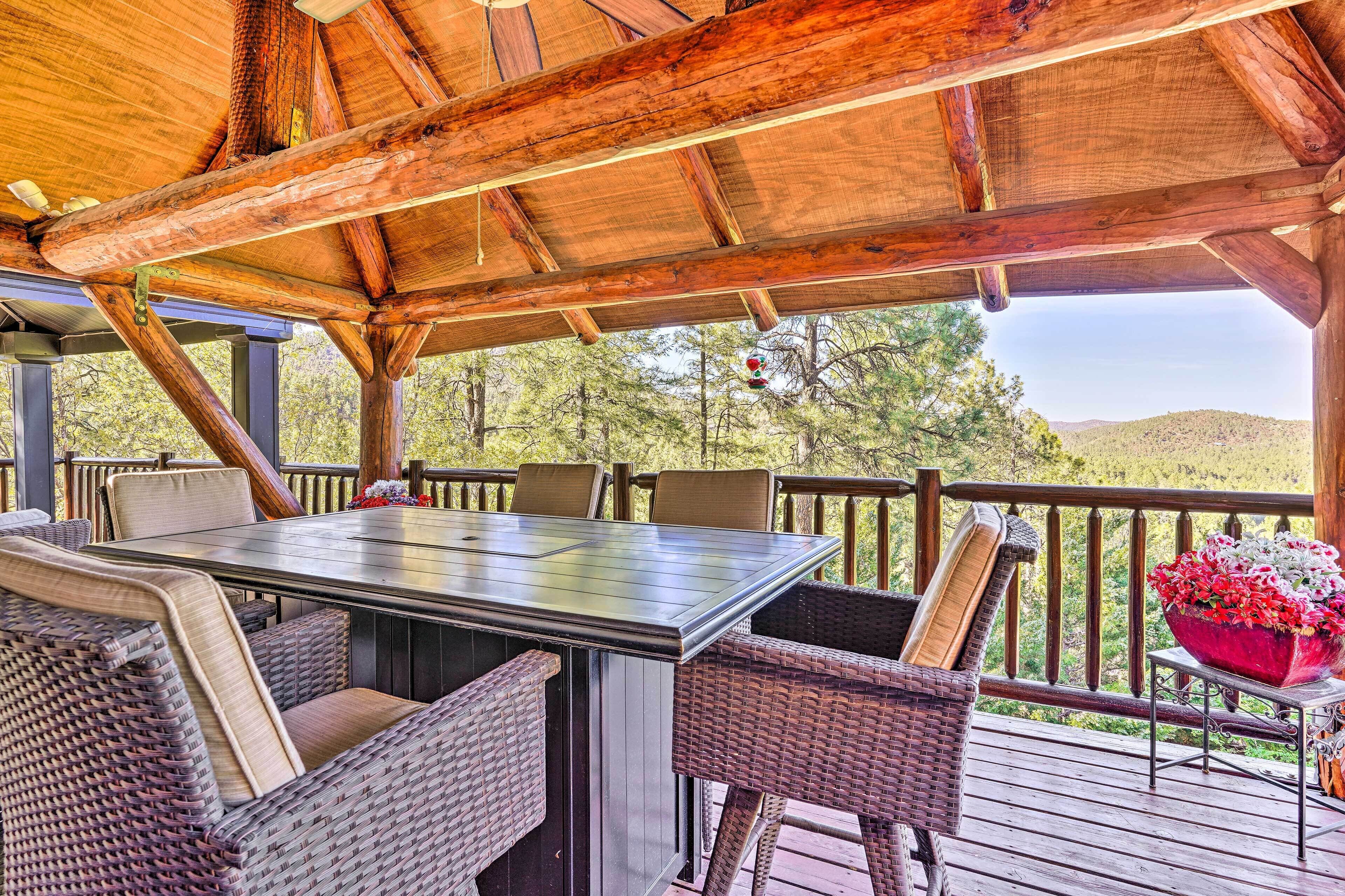 Un espacio de estar techado al aire libre con una mesa y sillas, con vistas a un paisaje natural.