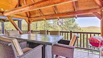 Un espacio de estar techado al aire libre con una mesa y sillas, con vistas a un paisaje natural.