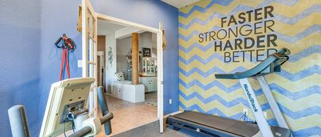 A fitness room with exercise equipment, a treadmill, and a motivational wall.