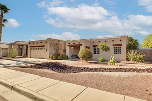 A single-story building with a flat roof, a garage, and a landscaped front yard with a variety of plants and a small tree. - Yuma Desert Oasis w/ Private Pool & Home Gym! (Yuma)