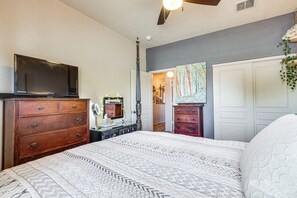 Ein Schlafzimmer mit Bett, Kommode, Fernseher und einem Bild an der Wand.