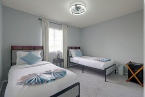 A hotel room with two single beds, a ceiling fan, a nightstand with a lamp, and a small table with a chair. - Kissimmee Family Fun w/ Private Pool & Pond Views! (Kissimmee)