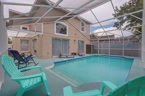 An indoor swimming pool with a covered area, two lounge chairs, and a poolside table. - Kissimmee Family Fun w/ Private Pool & Pond Views! (Kissimmee)