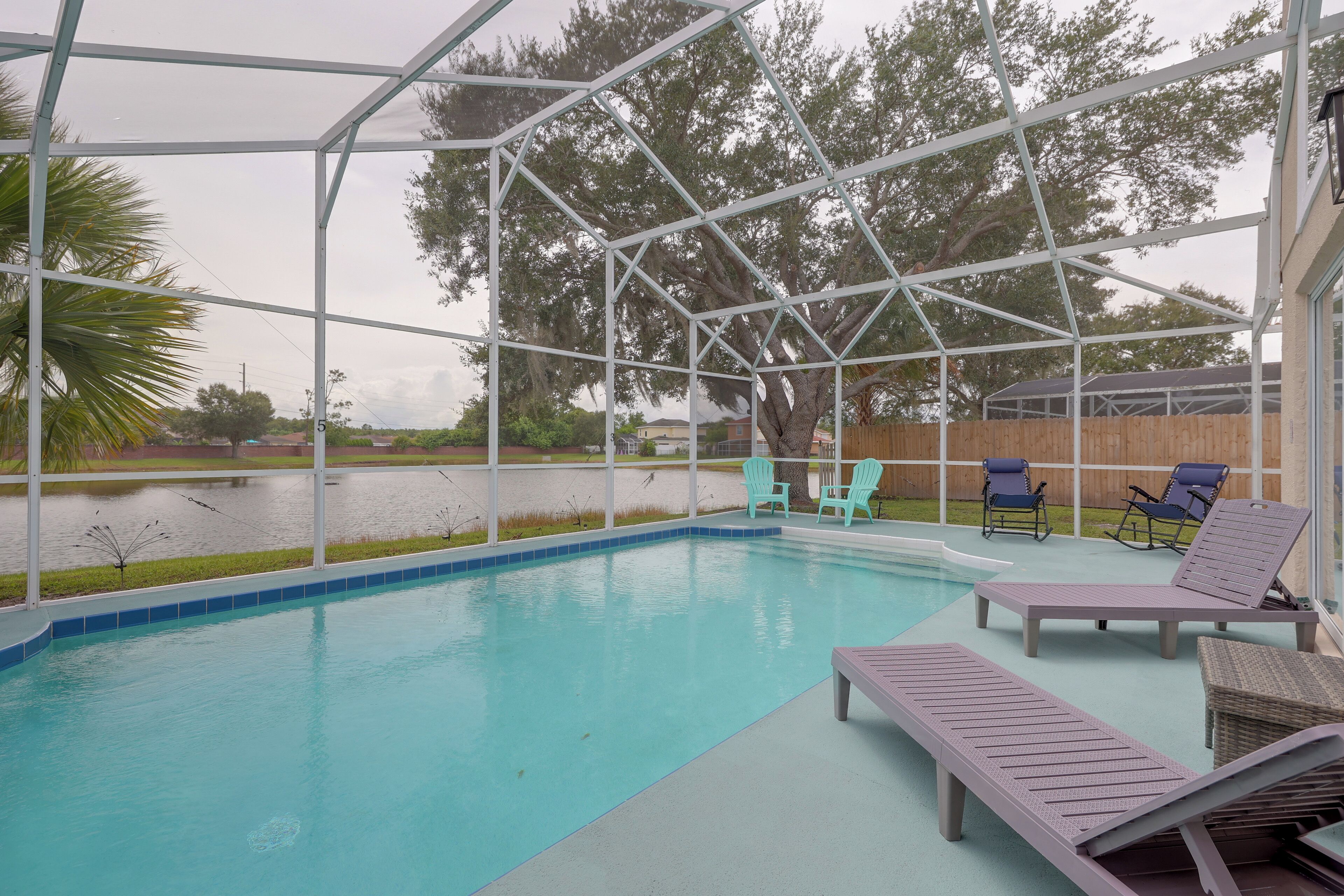 A covered outdoor swimming pool with lounge chairs and Adirondack chairs.