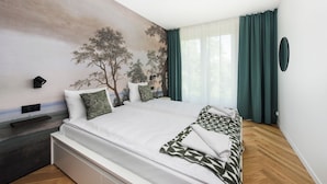 Un dormitorio con una cama grande, un televisor montado en la pared y una ventana con cortinas.