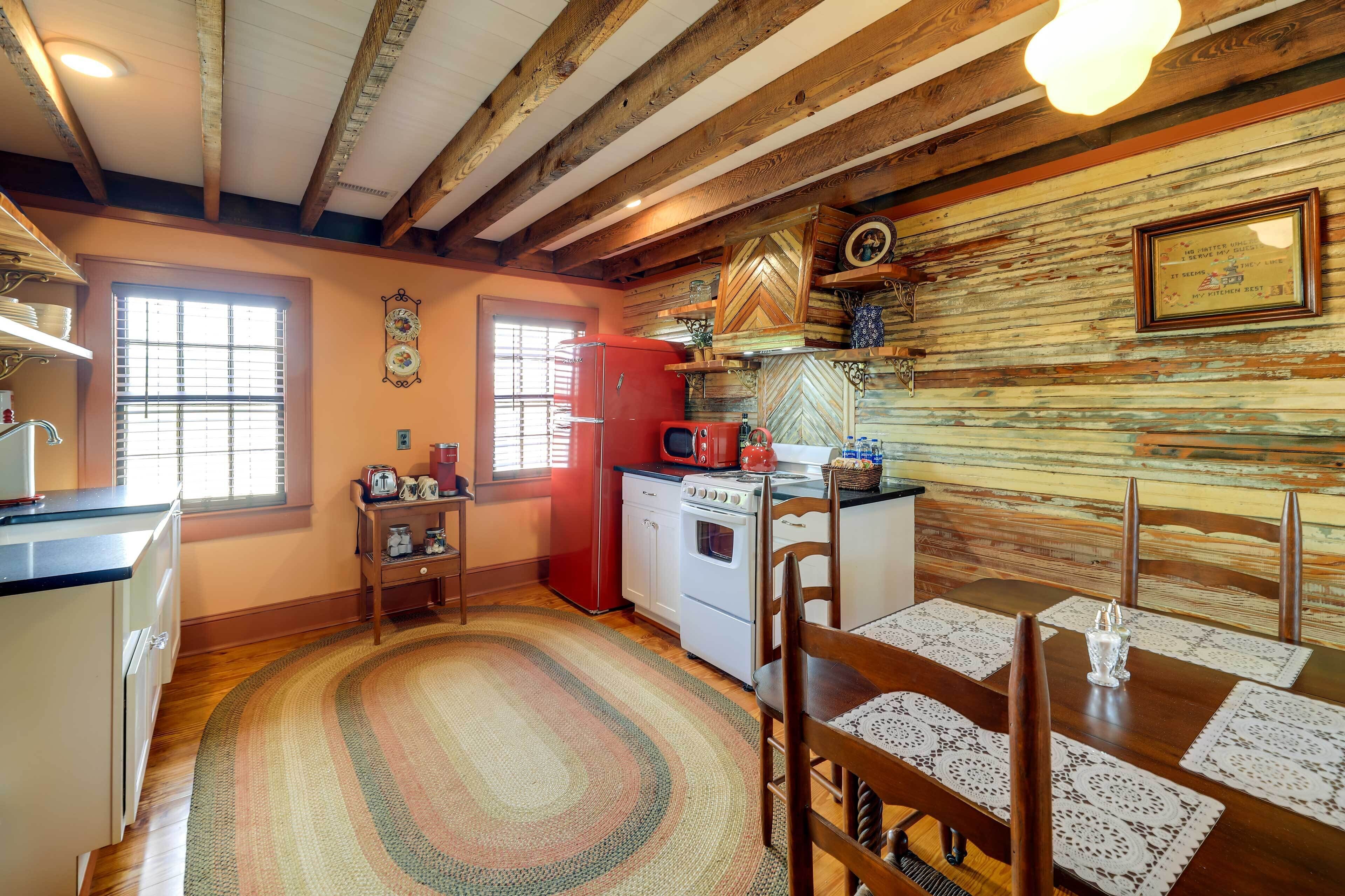 Una cocina con vigas de madera, un refrigerador rojo, una estufa y una mesa de comedor con sillas.