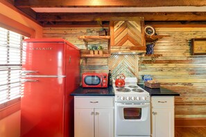 A compact kitchen with a red refrigerator, white stove, and a microwave. - Twin Victorian Apts in Downtown New Bern (New Bern)