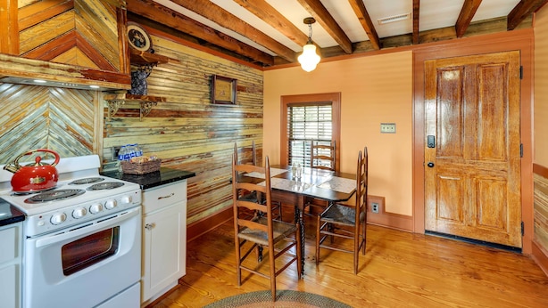 A kitchen with wooden beams, a stove, and a dining table with chairs. - Twin Victorian Apts in Downtown New Bern (New Bern)