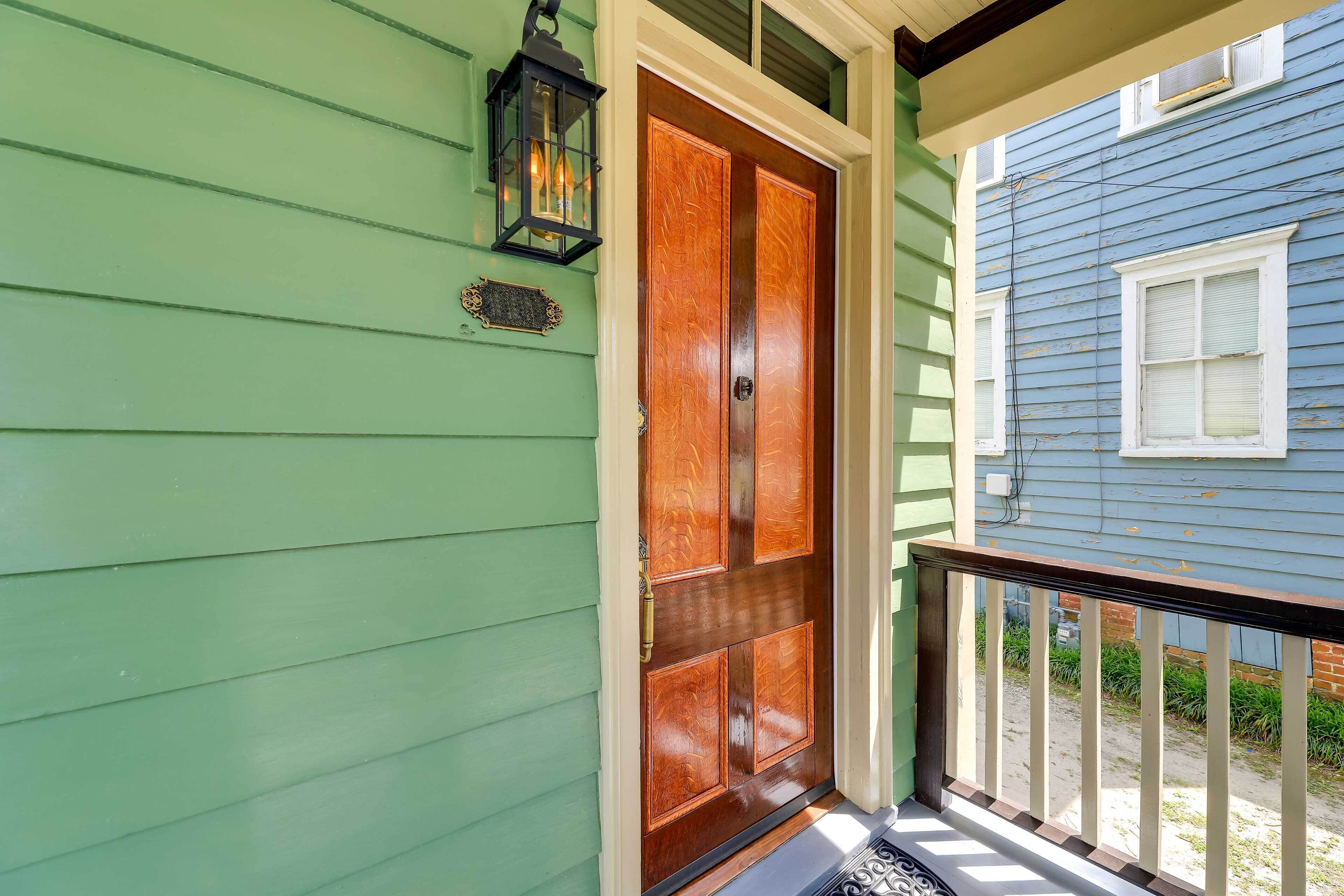 A green house with a wooden double door and a black lantern on the wall.