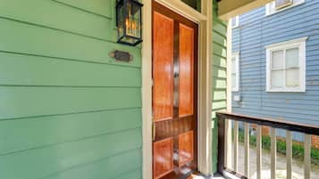 A green house with a wooden double door and a black lantern on the wall.