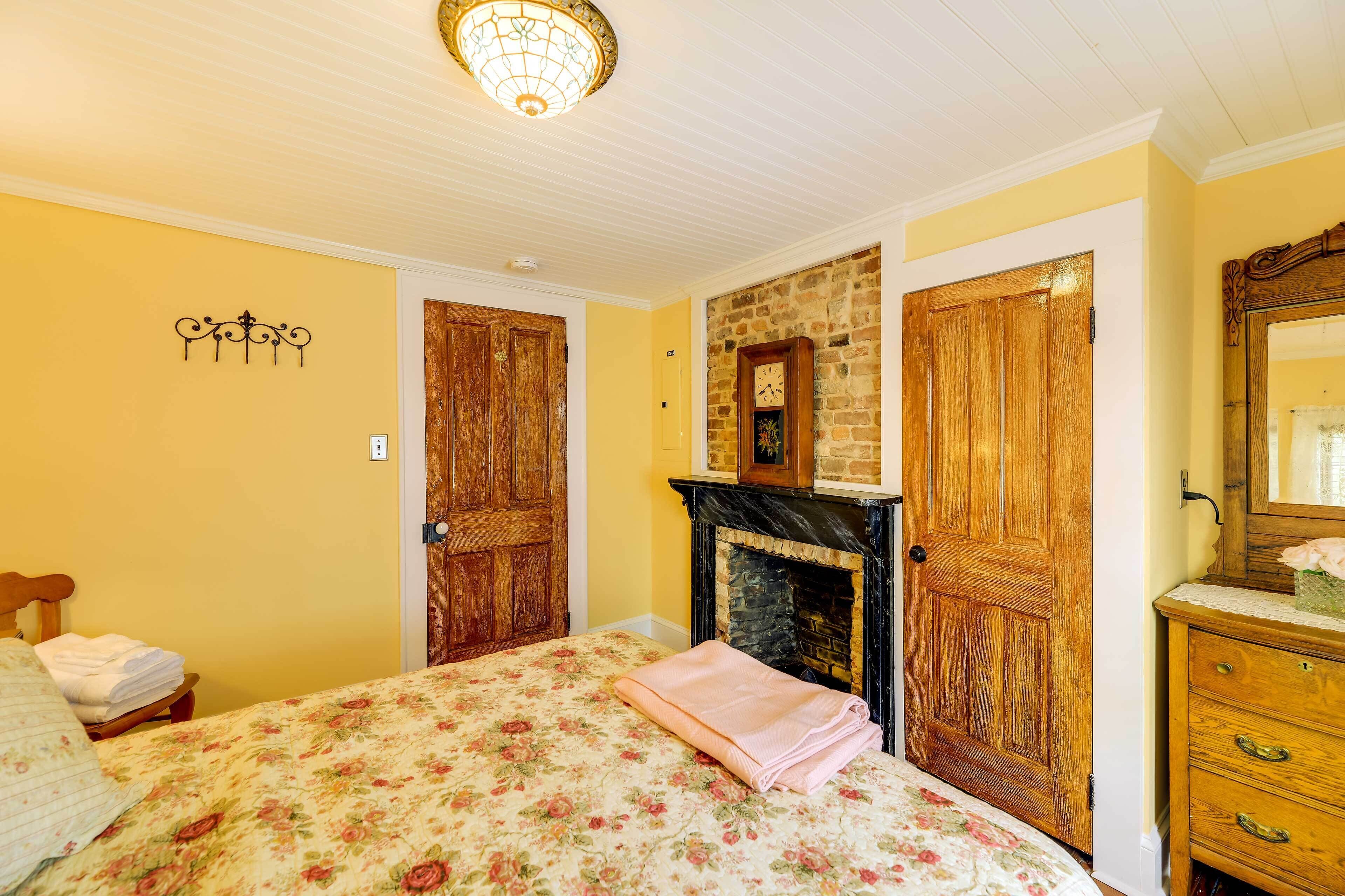 A bedroom with a bed, a fireplace, wooden doors, and a dresser.