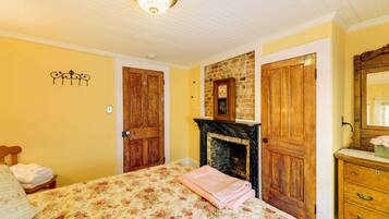 A bedroom with a bed, a fireplace, wooden doors, and a dresser.