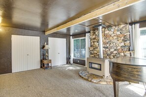 A room with a stone wall, a fireplace, and a large window. - Walkable Home in Cedar City With Ample Parking (Cedar City)