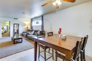 A spacious living room with a wooden dining table, leather sofa, and a ceiling fan. - Walkable Home in Cedar City With Ample Parking (Cedar City)