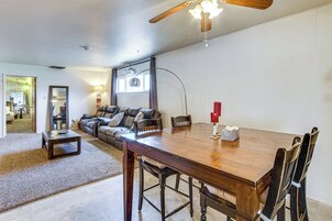 A spacious living room with a wooden dining table, leather sofa, and a ceiling fan.