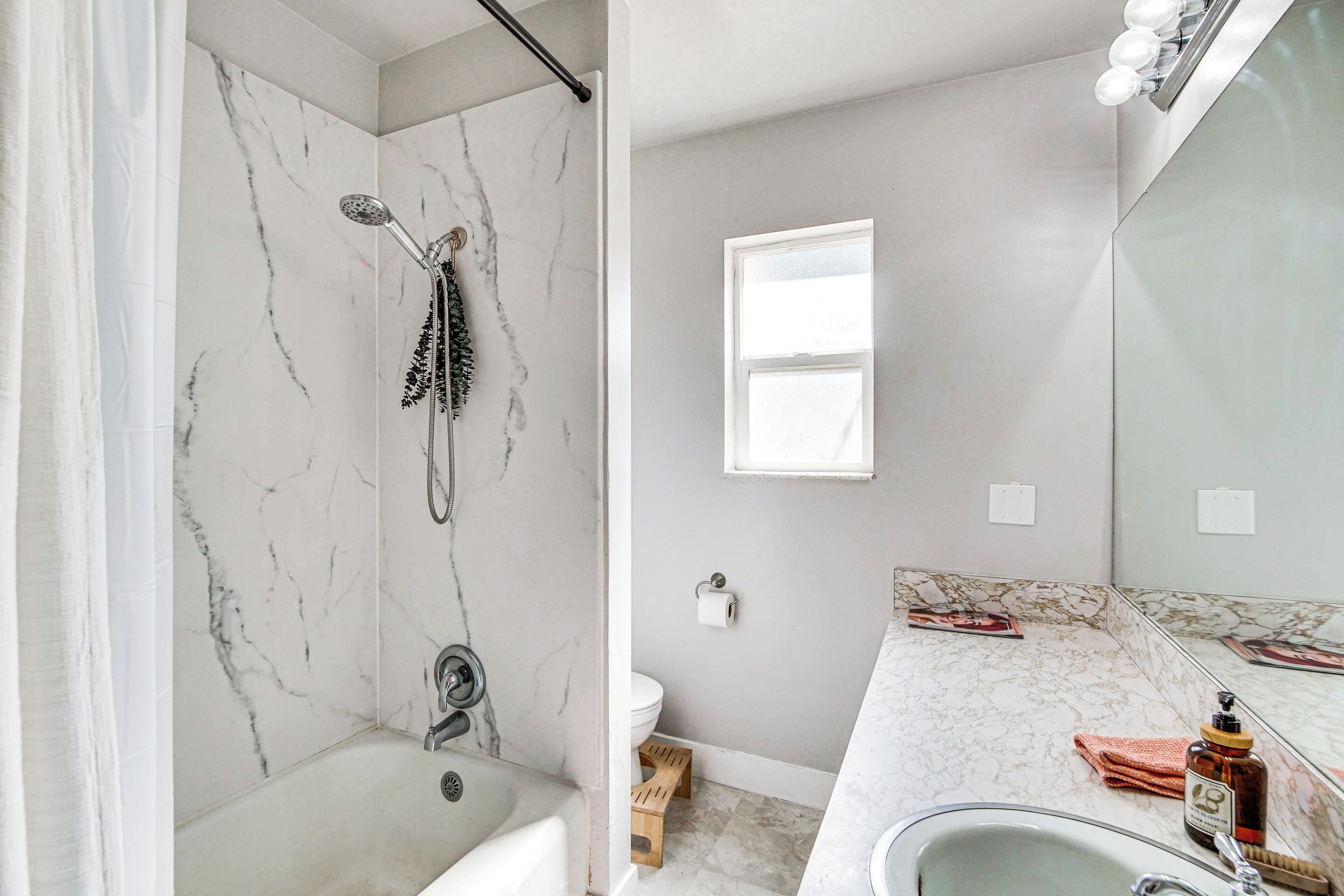 A bathroom with a shower, toilet, sink, and a mirror.