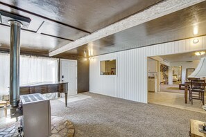 A spacious room with a large piano, a stone fireplace, and a view into another room with a dining area. - Walkable Home in Cedar City With Ample Parking (Cedar City)