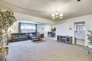 Una sala de estar con sofá, mesa de centro y chimenea. Se observa un comedor con sillas y una mesa, además de una cocina visible a través de una puerta abierta.