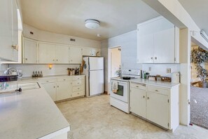 A kitchen with white cabinets, a refrigerator, a stove, and a sink. - Walkable Home in Cedar City With Ample Parking (Cedar City)