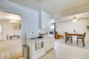 Una cocina con armarios blancos, una estufa y un comedor con mesa y sillas.