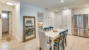 A modern kitchen with a built-in refrigerator, a dining area with a table and chairs, and a hallway leading to a bedroom. - Walk to Beach! Atlantic Beach Extended Stay (Atlantic Beach)