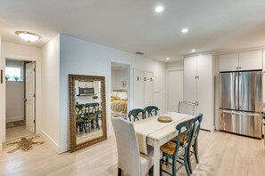 A modern kitchen with a built-in refrigerator, a dining area with a table and chairs, and a hallway leading to a bedroom. - Walk to Beach! Atlantic Beach Extended Stay (Atlantic Beach)