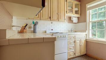 A kitchen with white cabinets, a stove, and a window.