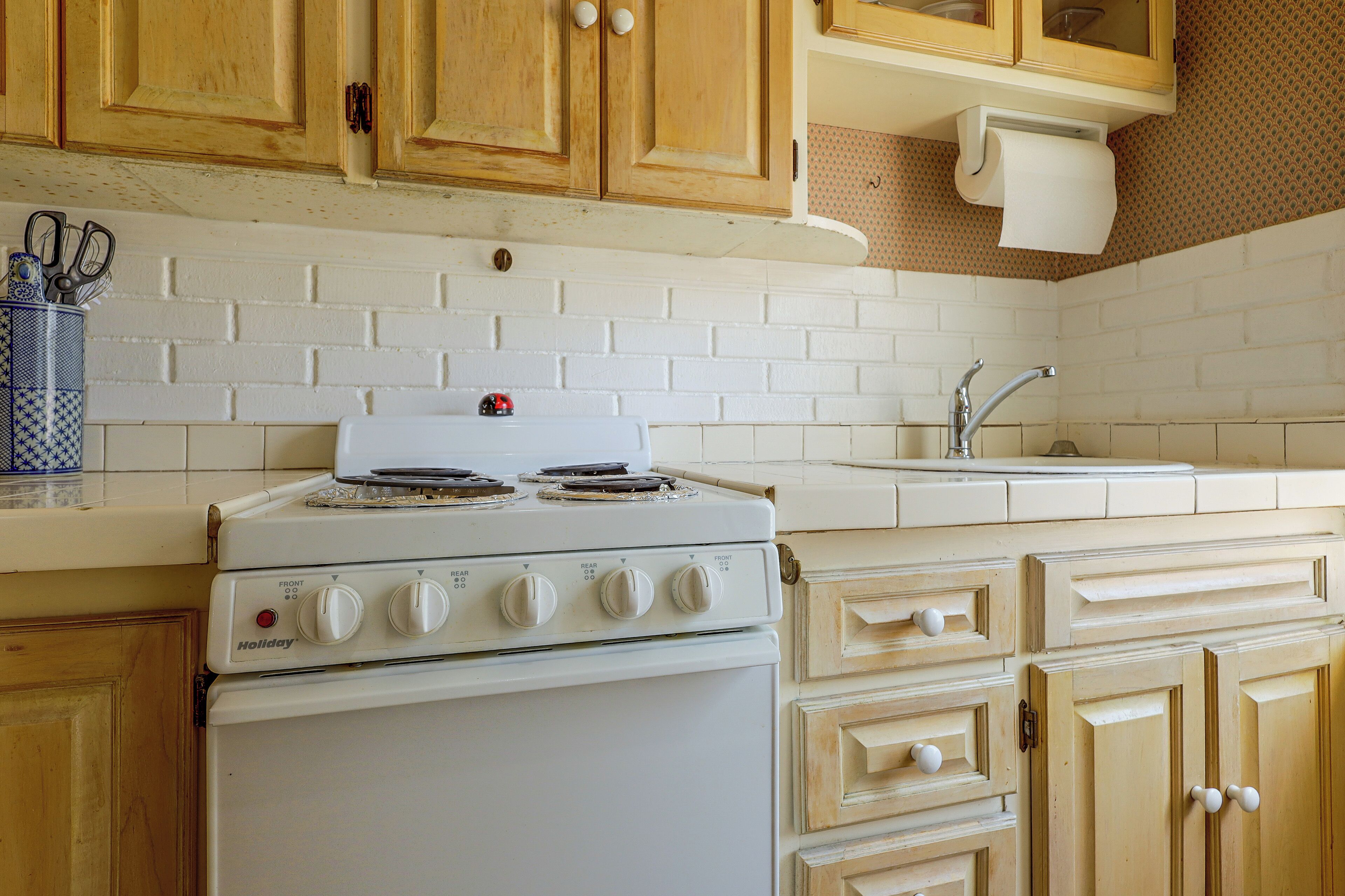 A kitchen with a white stove, wooden cabinets, and a white sink.