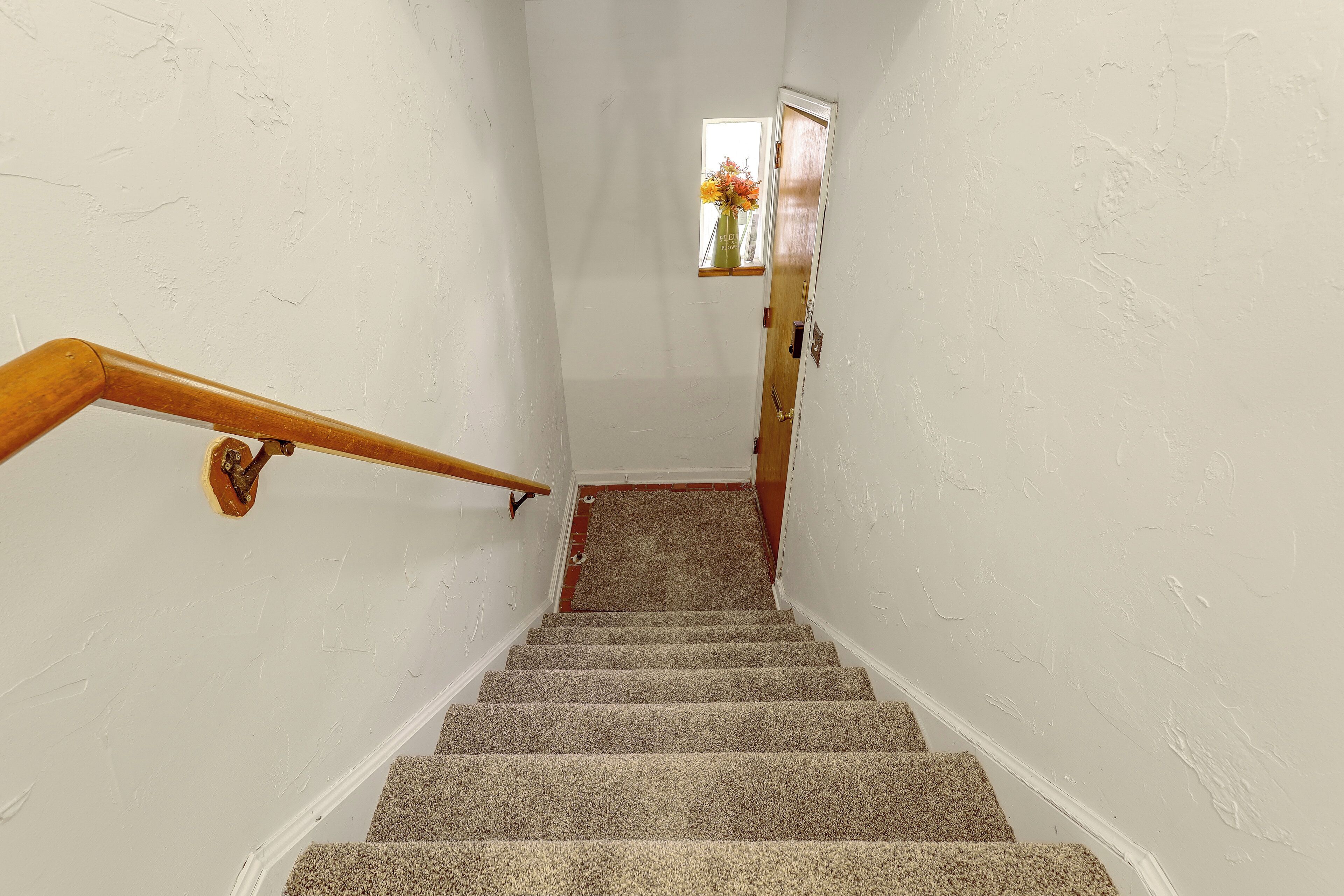 A staircase with a wooden handrail leading to a landing.