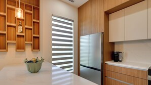Eine moderne Küche mit einem Edelstahl-Kühlschrank, Holzschränken und einer weißen Arbeitsplatte.