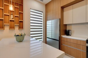 A modern kitchen with a stainless steel refrigerator, wooden cabinets, and a white countertop. - 4 Mi to Dtwn Mcallen, Sleek Couples Condo! (McAllen)