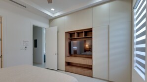 Ein Schlafzimmer mit Bett, Kleiderschrank, Fernseher und einem Fenster mit Jalousien.