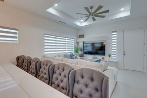 Ein modernes Wohnzimmer mit einem großzügigen Ecksofa, einem Deckenventilator und einem flachbildfernseher an der Wand.