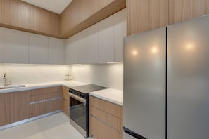 A modern kitchen with wooden cabinets, a stainless steel refrigerator, a built-in oven, and a white countertop. - Modern Couples Condo, 4 Mi to Downtown Mcallen! (McAllen)