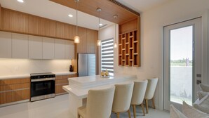 A modern kitchen with a central island, bar stools, built-in wooden cabinets, and a large window. - Modern Couples Condo, 4 Mi to Downtown Mcallen! (McAllen)
