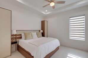 A bedroom with a bed, nightstands, a ceiling fan, and a window with blinds. - Modern Couples Condo, 4 Mi to Downtown Mcallen! (McAllen)