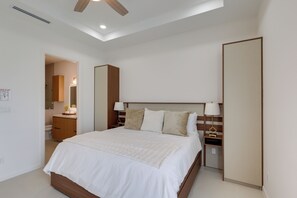 Ein Hotelzimmer mit Bett, Nachttischen, einem Spiegel und einem Deckenventilator.