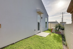A narrow, grassy pathway leading to a white building with a door and windows. - Modern Couples Condo, 4 Mi to Downtown Mcallen! (McAllen)