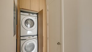 A laundry room with two white Samsung washing machines, wooden cabinets, and a door. - Modern Couples Condo, 4 Mi to Downtown Mcallen! (McAllen)