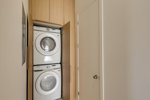 Ein Waschraum mit zwei weißen Samsung Waschmaschinen, Holzschränken und einer Tür.