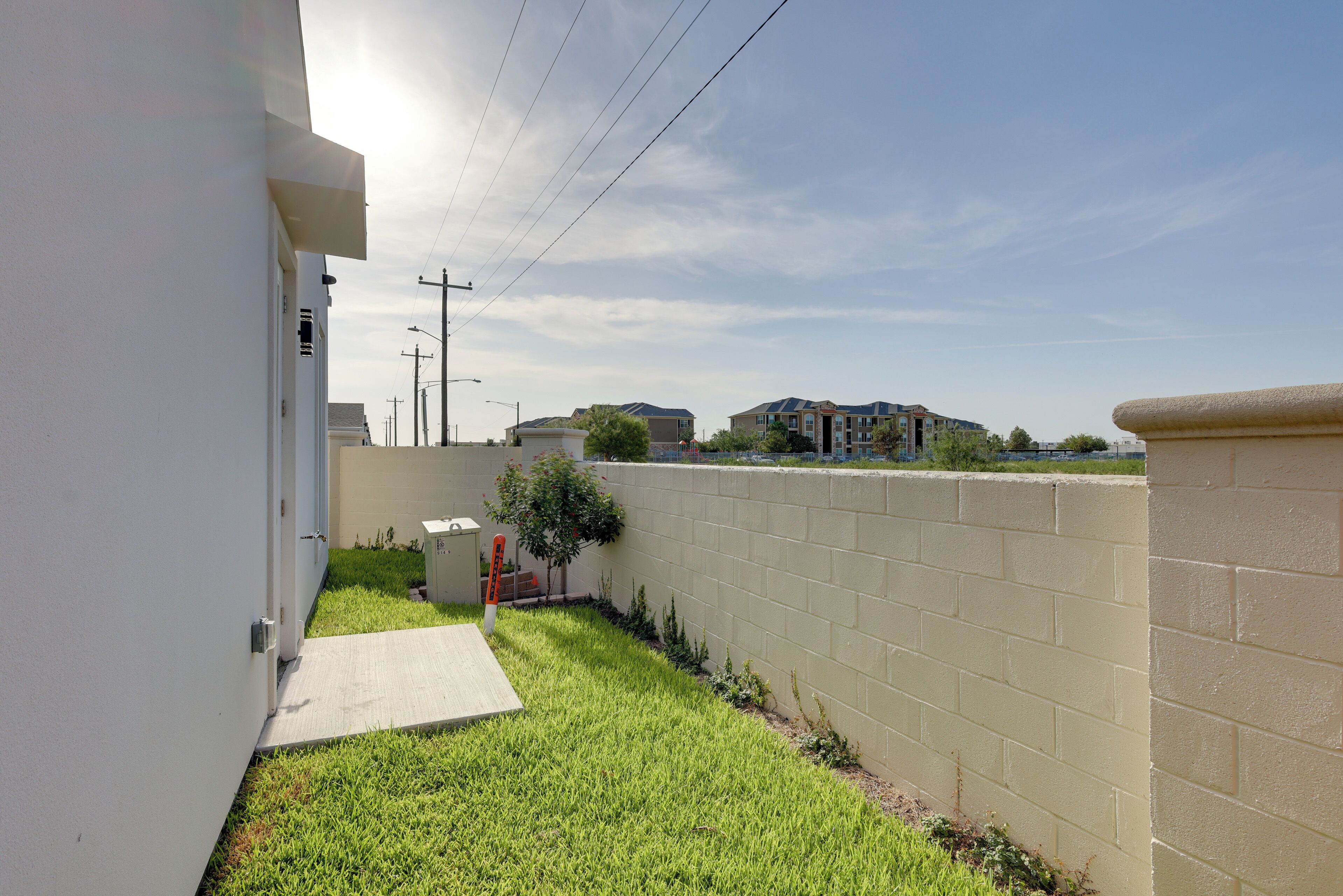 Un quartier résidentiel avec un chemin pavé, une petite pelouse, un mur de briques et un bâtiment en arrière-plan.