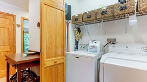 A laundry area with a Maytag washer and dryer, a wooden table, and wicker baskets labeled with laundry items. - Serene Wooded Cabin w/ Decks, 4 Mi to Dtwn Murphy (Murphy)