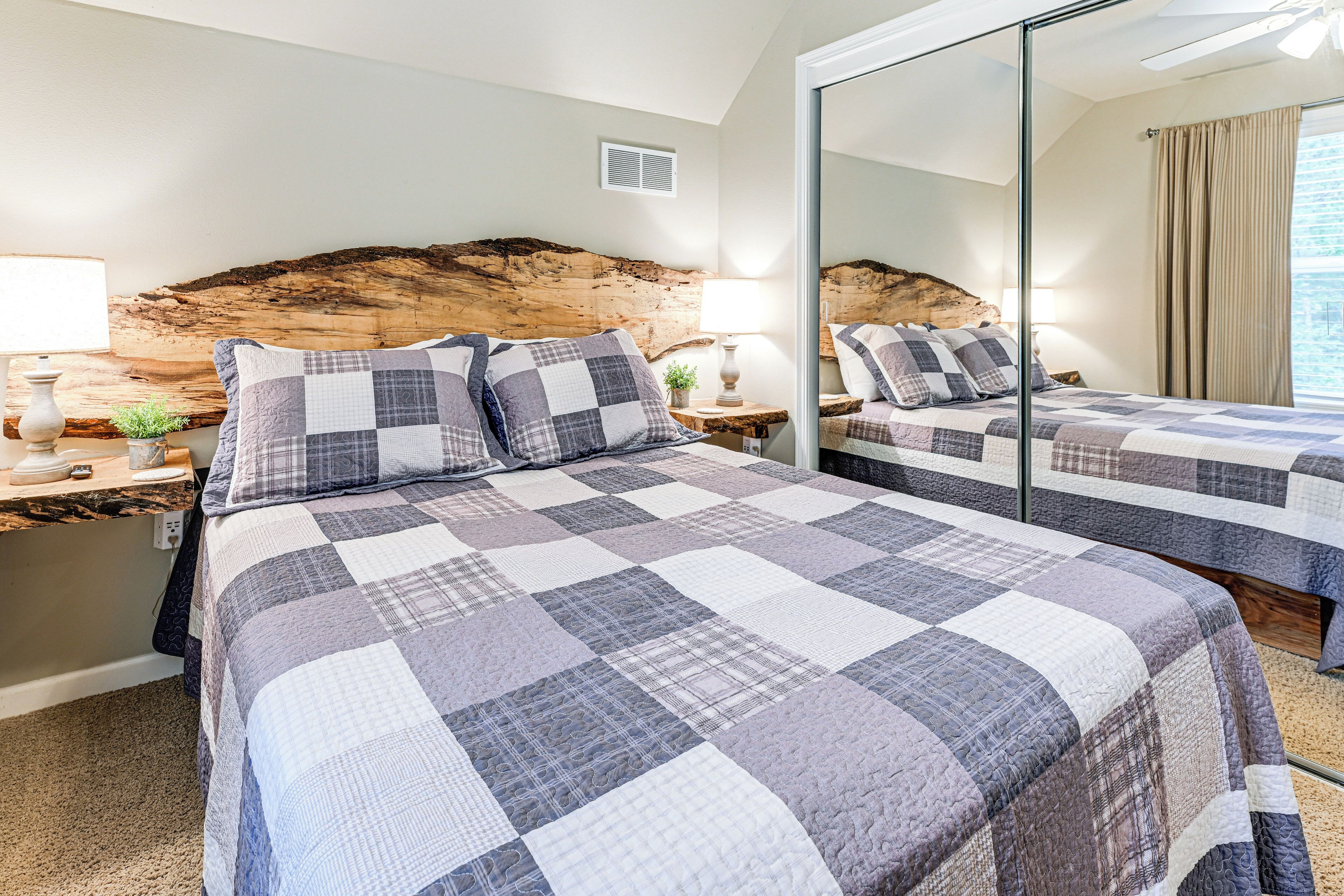 A bedroom with a large bed, a nightstand, a mirror, and a headboard made of wood.